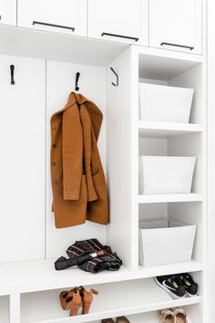 a coat and shoes are sitting on the shelf in this white closet with open doors