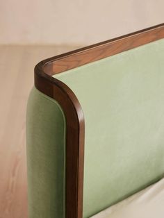 a close up of a green chair with wood trim on the armrests and back