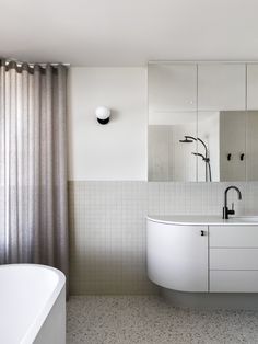 a white bath tub sitting next to a bathroom sink under a mirror and light fixture