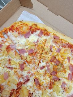 a pizza with ham and pineapple slices in a box