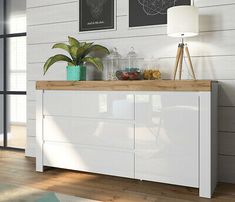 a white buffet table with two pictures on the wall