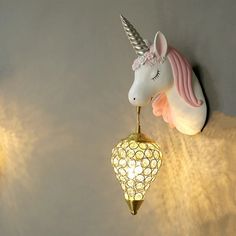 two lights that are on the side of a wall with a unicorn head hanging from it