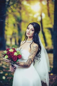 a woman with tattoos holding a bouquet of flowers