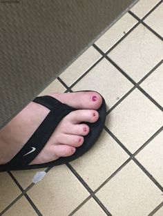 a person's foot with pink nail polish on it and a black sandal