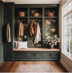 a room filled with lots of green cupboards and flowers on the wall next to a window