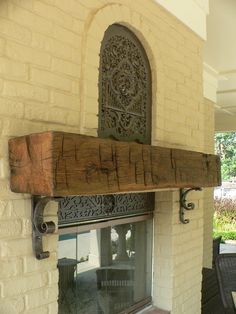 an outdoor fireplace with a wooden mantle and decorative iron work on the front window sill