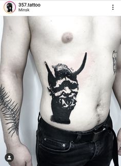 a man with a bull tattoo on his stomach is standing in front of a white wall