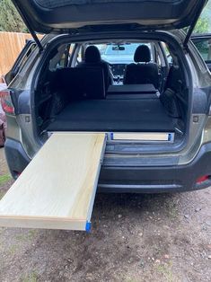 the back end of a car with its trunk open and wood planks in place