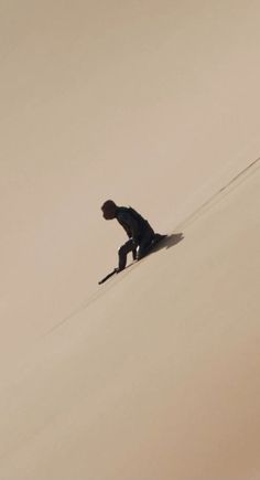 a man riding skis down the side of a snow covered slope on top of a sandy hill