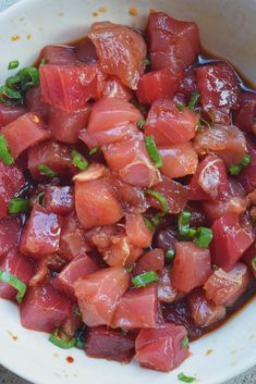 a white bowl filled with chopped up meat and green garnish on top of it