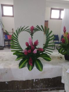 some pink flowers and green leaves are on a white table cloth in the middle of a room