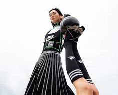 a woman in a black and white dress with her hands on her head while wearing a pair of gloves