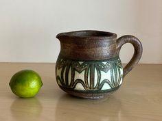 a green lime sitting next to a ceramic pitcher