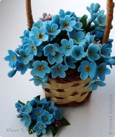 small blue flowers are in a basket next to some straw baskets on a white surface