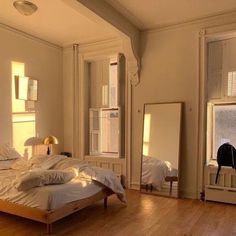 a bed sitting in the middle of a bedroom next to a dresser and mirror on top of a hard wood floor