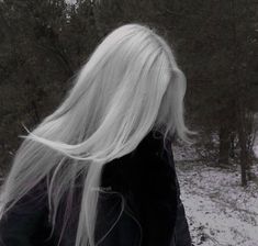 a woman with long white hair walking in the snow