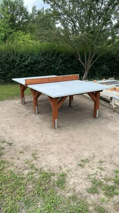 a ping pong table sitting on top of a dirt field next to a tree