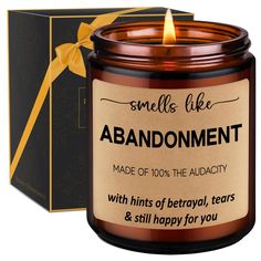 a candle that is next to a box with a yellow ribbon on it and the words, smell like abondment made of 100 % the audact