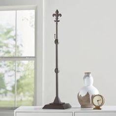 a lamp, vase and clock are on a white table in front of a window