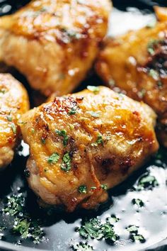 some chicken is cooking in a pan with sauce and herbs on the side, ready to be eaten