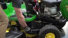 a man standing next to a green lawn mower