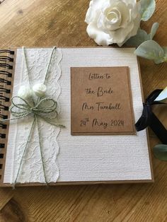 a wedding guest book on a table with flowers and ribbon tied around the cover, which reads letters to the bride