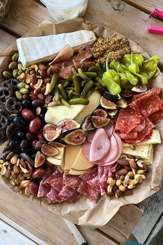 an assortment of meats and cheeses on a wooden table