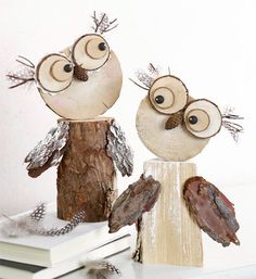 two wooden owls sitting on top of a white table next to a stack of books