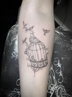 a small birdcage tattoo on the right arm and leg, with birds flying around it