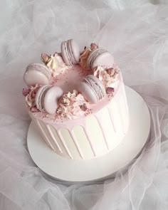 a white cake with pink frosting and macaroons on top