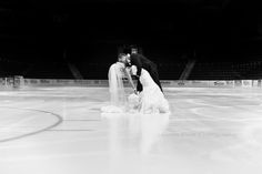 a bride and groom kiss on the ice at an indoor hockey rink in black and white