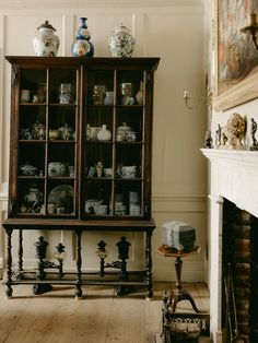 an antique china cabinet in the corner of a room with white walls and wood floors