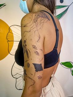 a woman wearing a face mask with tattoos on her back