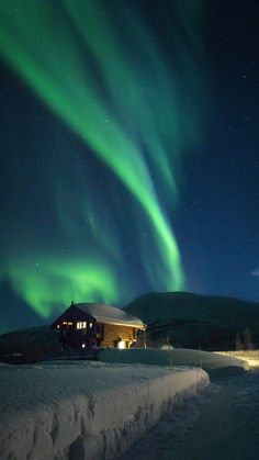 the aurora bore is shining brightly in the sky above a cabin and snow covered ground