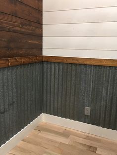 the corner of a room with wood flooring and corrugated siding on the wall,