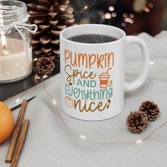 a cup of coffee sitting on top of a table next to some cinnamons and pine cones