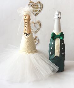 two wine bottles decorated with tulle and bows, next to a bottle shaped like a christmas tree