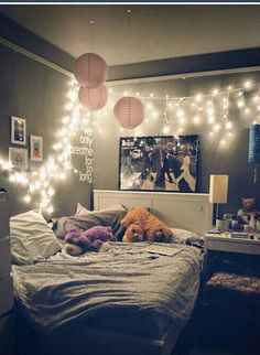 a bedroom with lights strung from the ceiling and stuffed animals on the bed in front of it