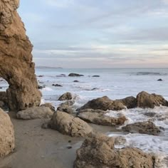 there is a rock formation on the beach by the water's edge with waves coming in