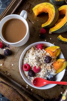 a bowl of oatmeal with berries and raspberries next to a cup of coffee