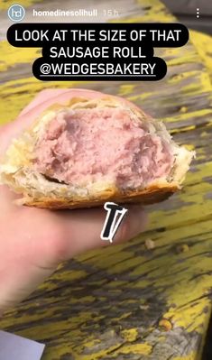 a person holding a half eaten sandwich in their hand with the words, look at the size of that sausage roll @ wedgesbakery