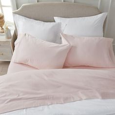 a bed with pink sheets and pillows in a bedroom