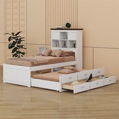 a white bed with drawers underneath it and a plant in the corner next to it