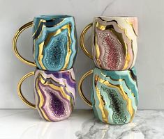 three coffee mugs are stacked on top of each other in different colors and designs