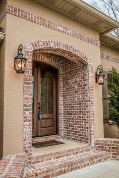 a brick building with a wooden door and two lights on the side of it's entrance