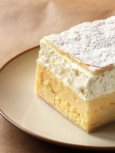 a piece of cake on a plate with powdered sugar on top, sitting on a table