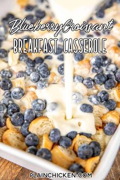 blueberry breakfast casserole is being drizzled with white cream and fresh blueberries