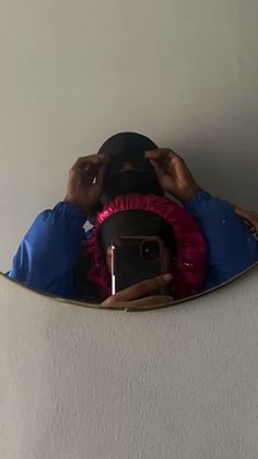 a person taking a selfie in the mirror with their cell phone and wearing a blue jacket