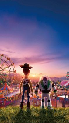 two toy figures standing in front of an amusement park with ferris wheel and carnival rides