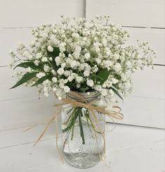 a mason jar filled with baby's breath flowers on a white wooden table top